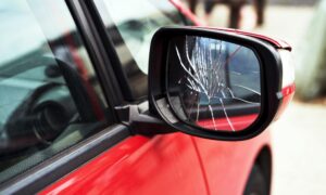 cracked side mirror on red car needing Houston auto glass repair
